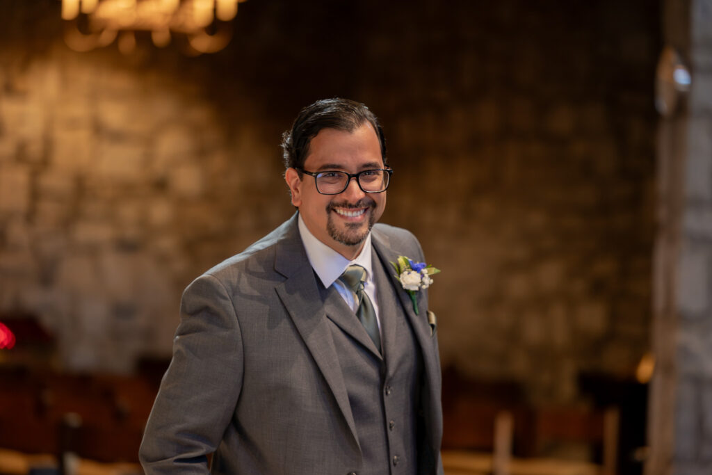 The groom smiling at the camera during the wedding ceremony.