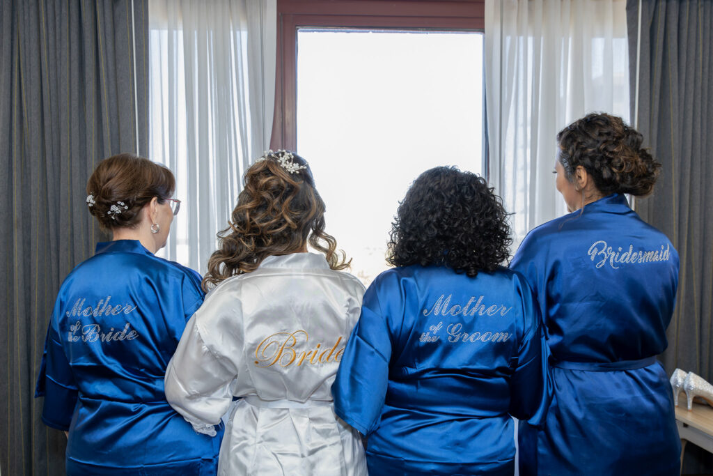 Bride with mother, mother of groom, and sister in robes getting ready.