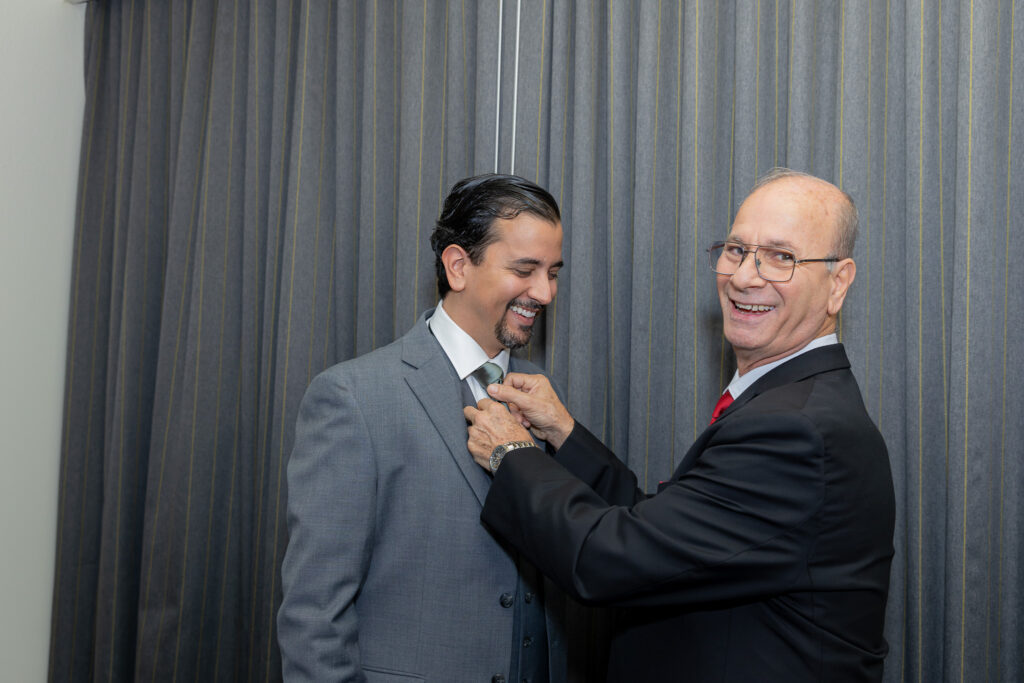 Groom with father getting ready. Father is adjusting groom's tie.