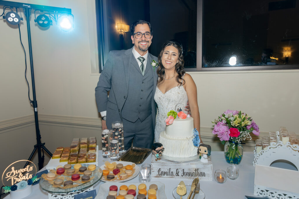 The bride and groom smiling at the camera before they cut into their wedding cake.