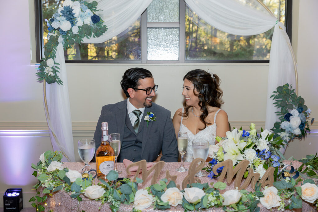 The bride and groom sitting at their reception table at each other.