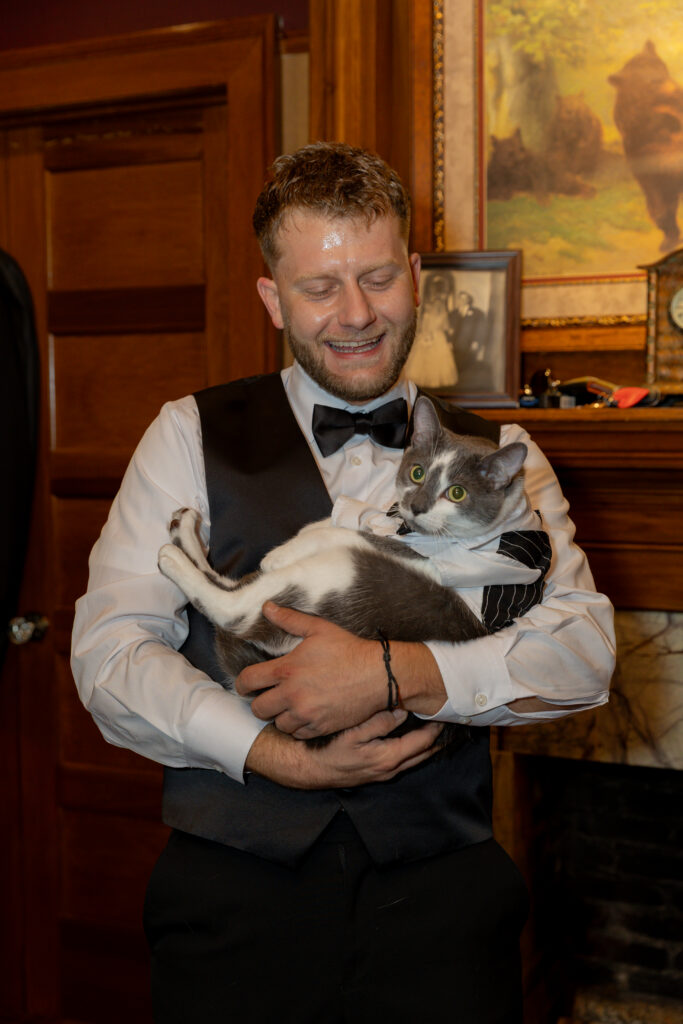 The groom holding their cat, who was part of the grooms.