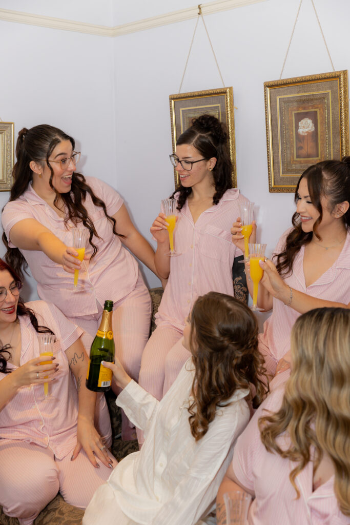 The bride and her bridesmaids cheersing drinks during their getting ready moments.