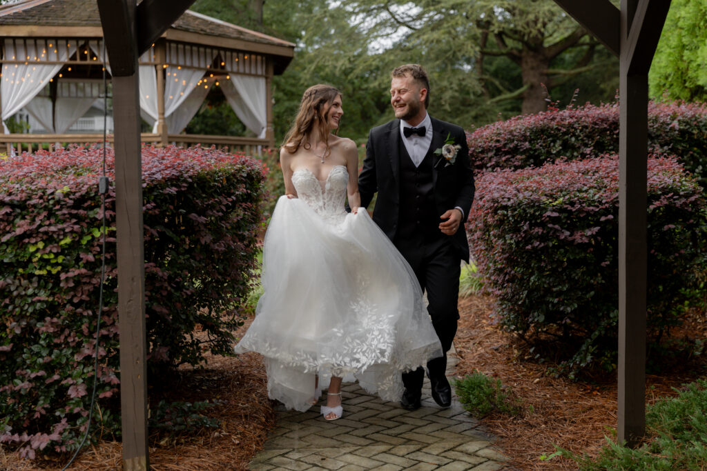 The bride and groom frolicing along one of the outdoor brick trails of the venue.