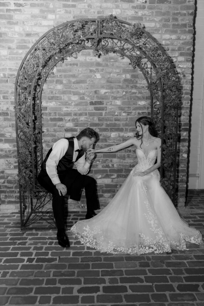 A couples portrait of the groom holding and kissing the bride's hand.