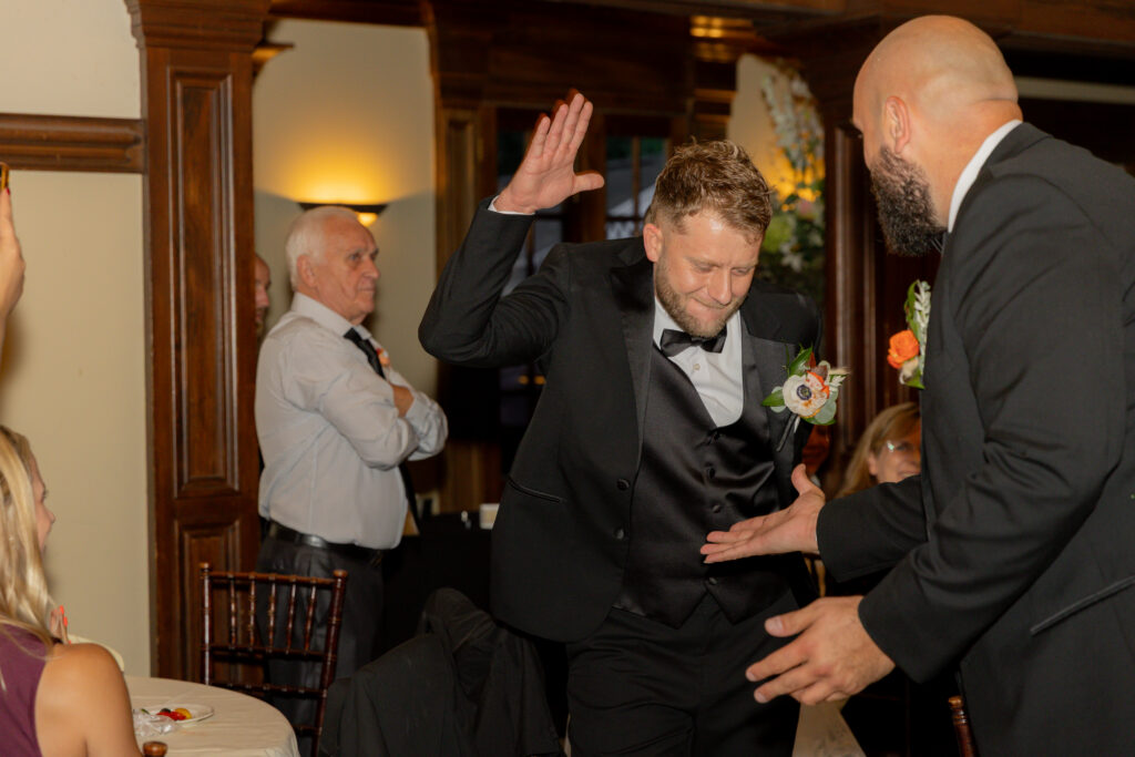 The groom and his groomsman sharing an epic high five during the reception.